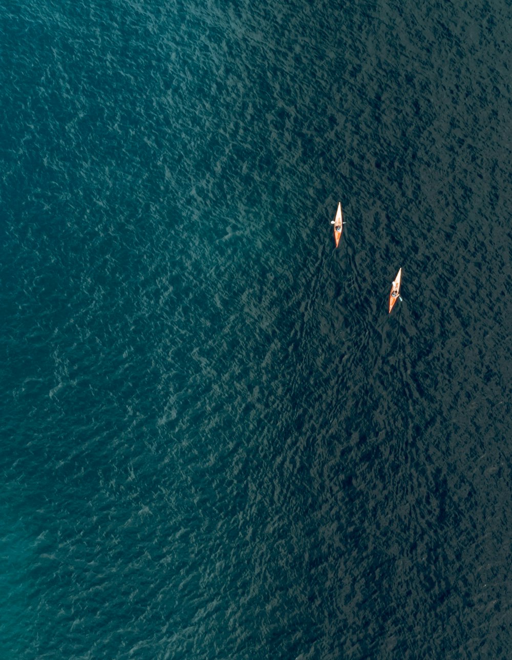 two small boats floating on top of a large body of water