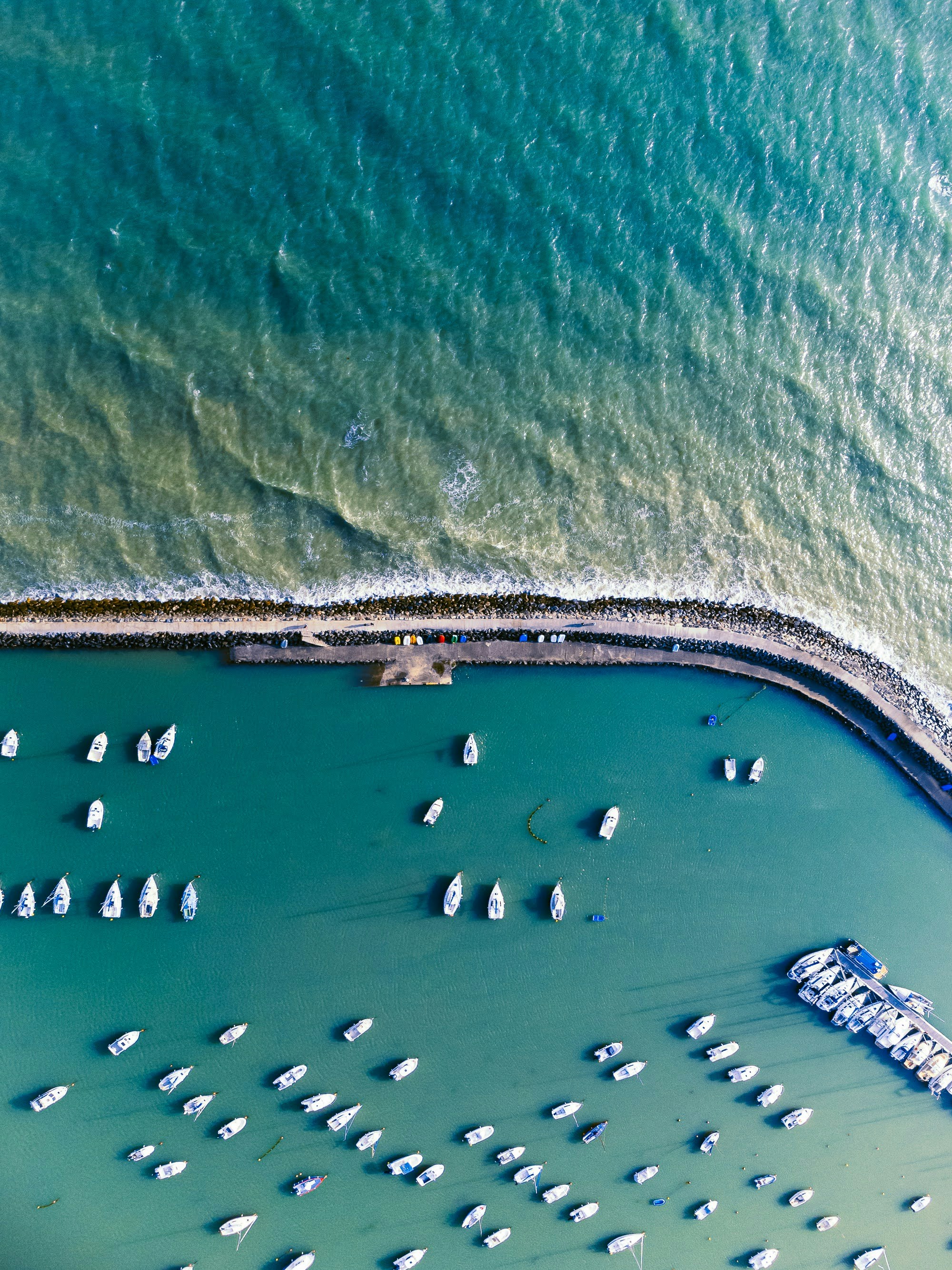 Aerial view of colorful fishing boats in turquoise Mediterranean harbor