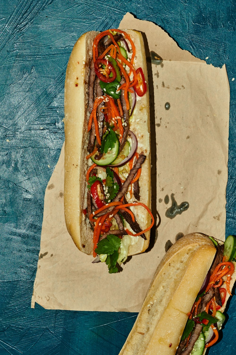 Due hot dog con diversi condimenti seduti su un pezzo di carta cerata