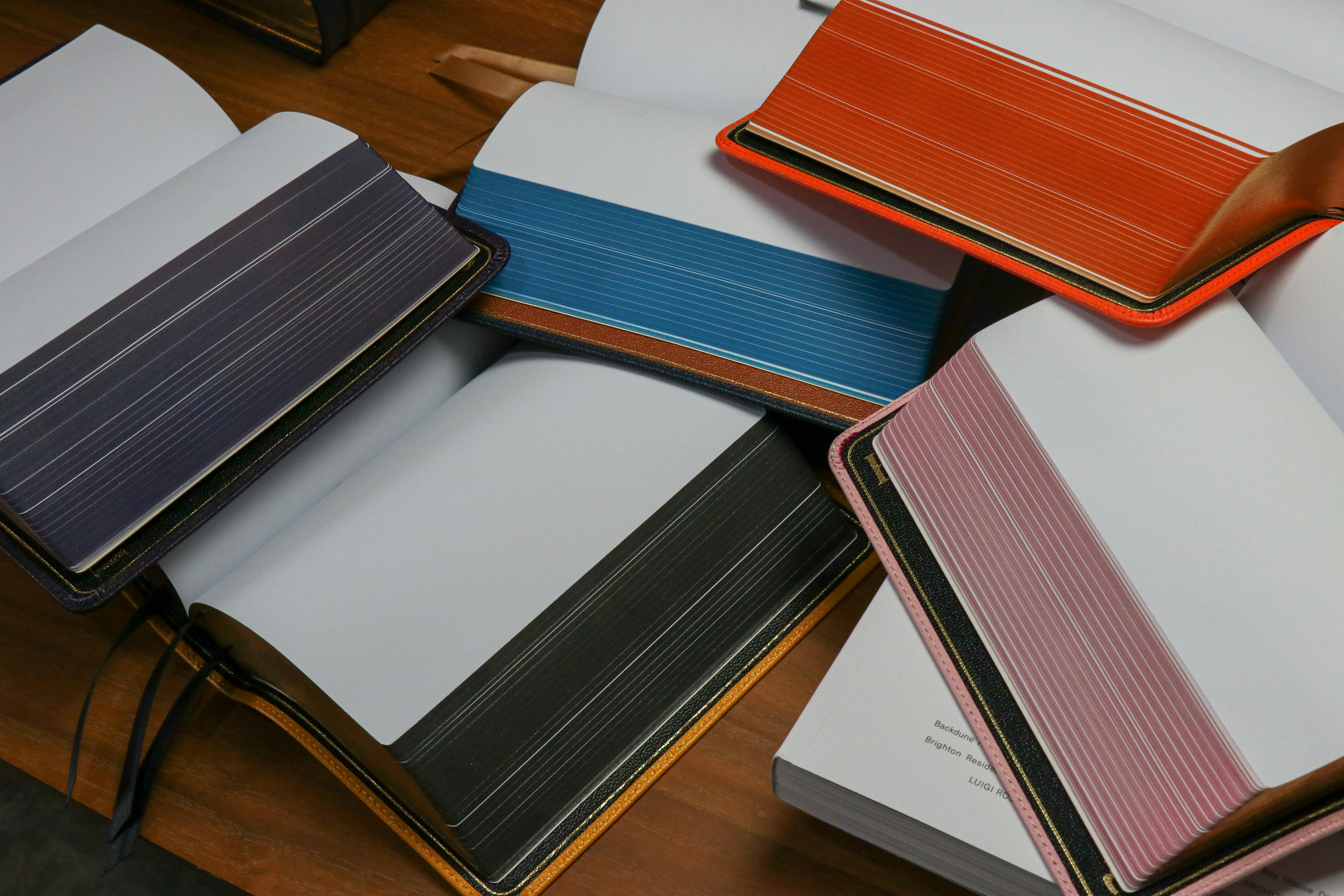 a pile of notebooks sitting on top of a wooden table