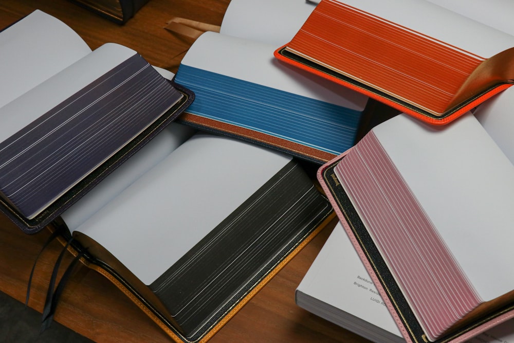 a pile of notebooks sitting on top of a wooden table