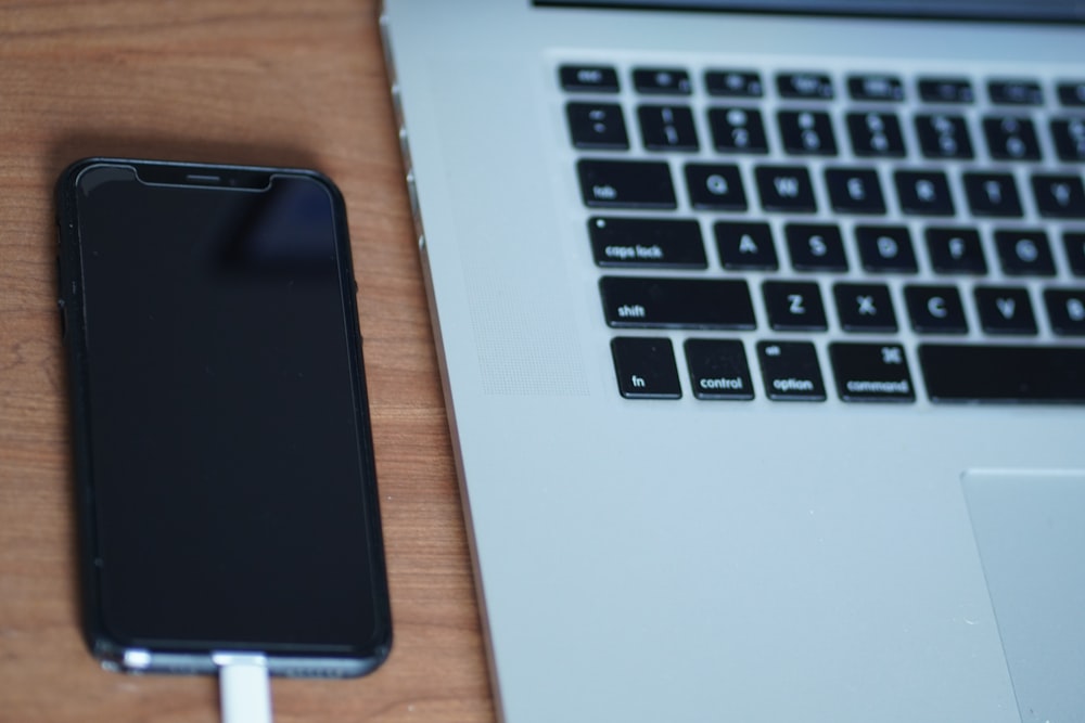 um telefone celular conectado a um carregador ao lado de um laptop