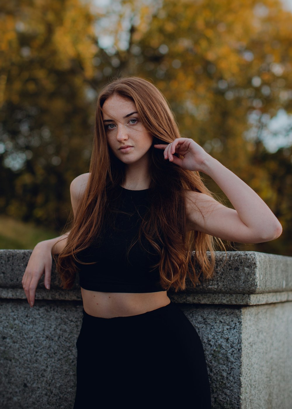 a woman with long hair leaning against a wall