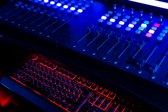 Close-up of soundboard sliders glowing with neon accents in a dark room.