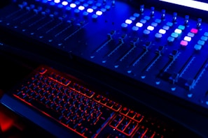Close-up of soundboard controls glowing in dim lighting.