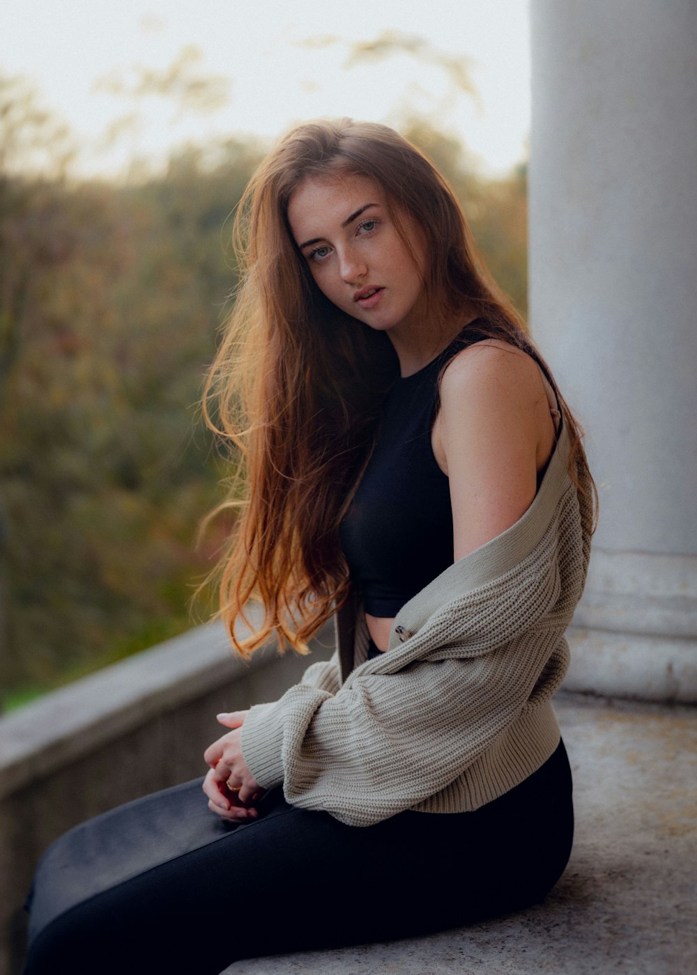 a woman with long hair sitting on a ledge