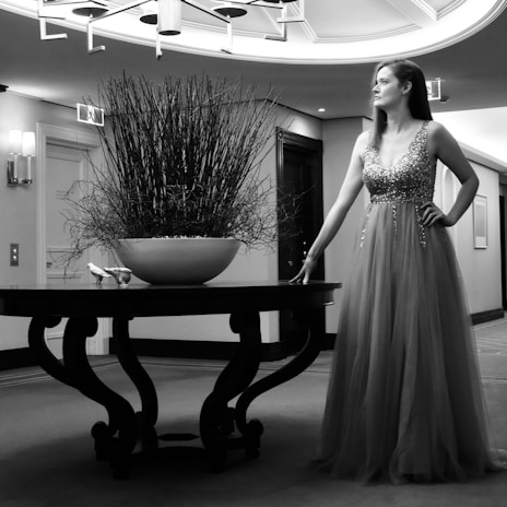 Elegant evening dress laid out with delicate accessories on a vintage wooden table under warm light.