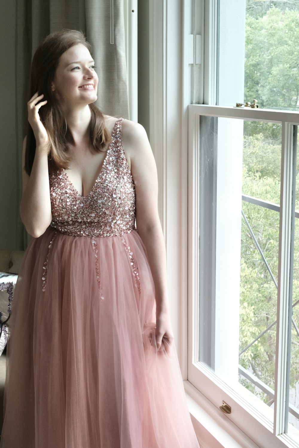 Foto Una mujer con un vestido rosa parada junto a una ventana Imagen Moda gratis en Unsplash