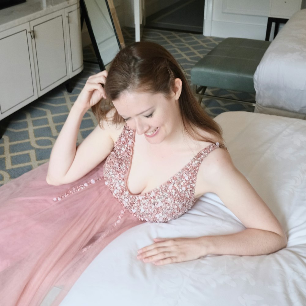 a woman in a pink dress laying on a bed