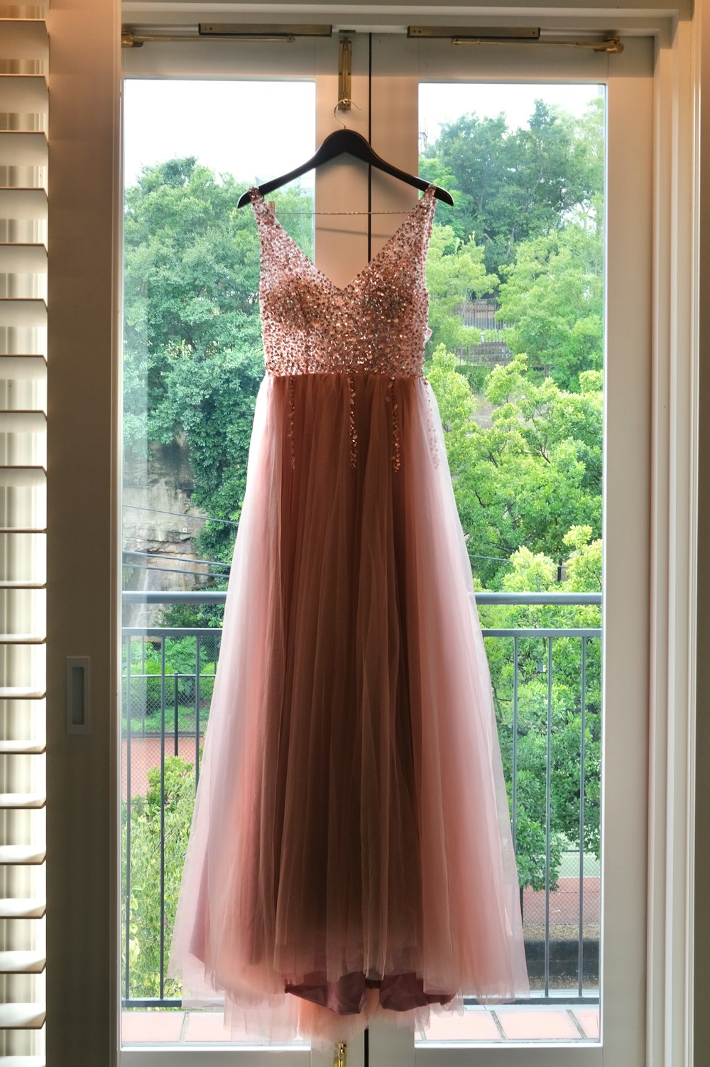 a dress hanging on a window sill in front of a window
