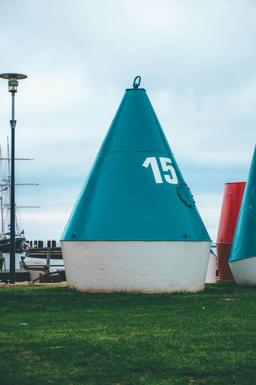 a large blue sail boat sitting on top of a lush green field