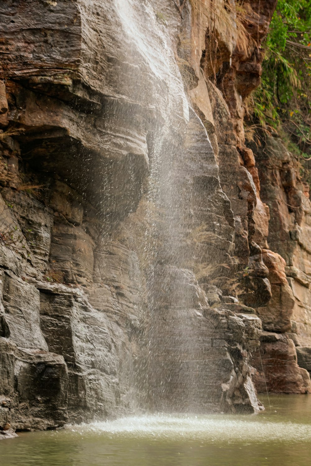 a man standing under a waterfall next to a body of water