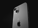 A close-up of the back of a smartphone with a prominent dual-camera module against a dark background. The phone has a sleek, modern design and features the recognizable logo of a major tech company.