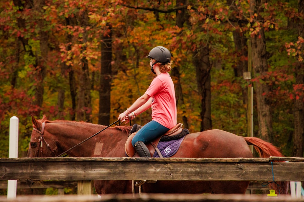 a woman riding on the back of a brown horse