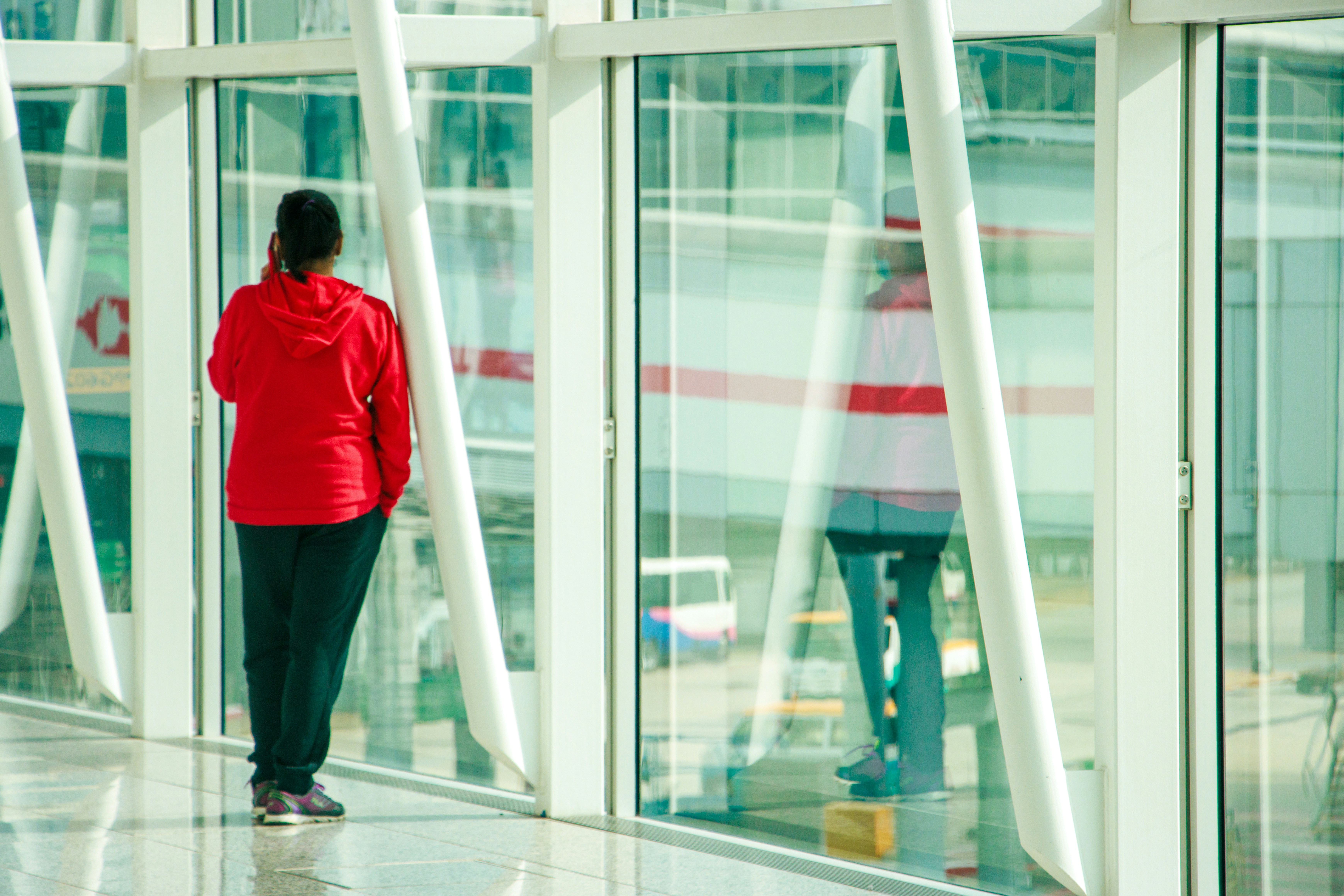 a woman in a red jacket standing in front of a window