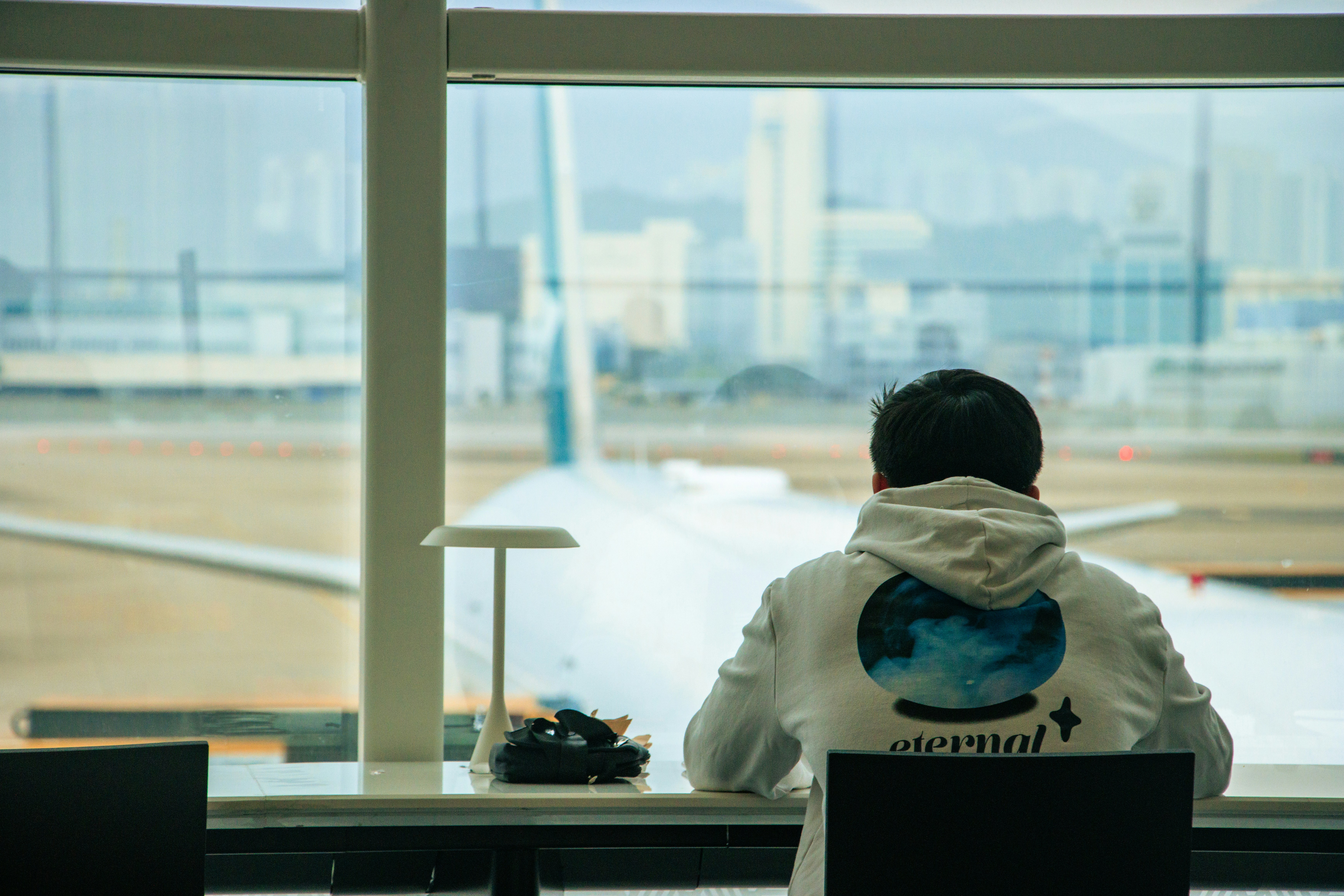 a person sitting in front of a window looking out at an airport, 