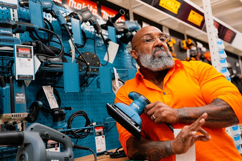 a man in an orange shirt is holding a tool