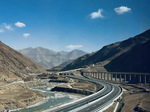 Aerial shot of a newly constructed highway weaving through a mountainous landscape.