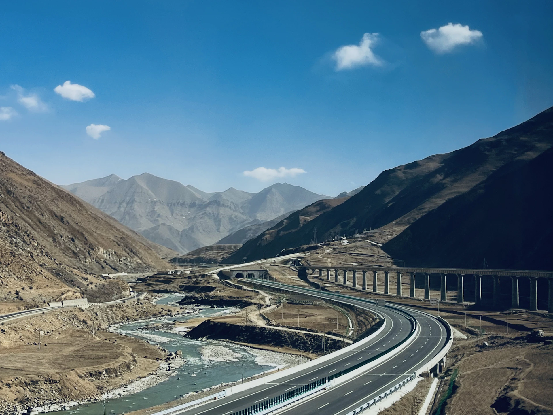 A panoramic view of a newly constructed highway cutting through the Andean mountains near Bogotá, showcasing modern engineering and smooth asphalt.