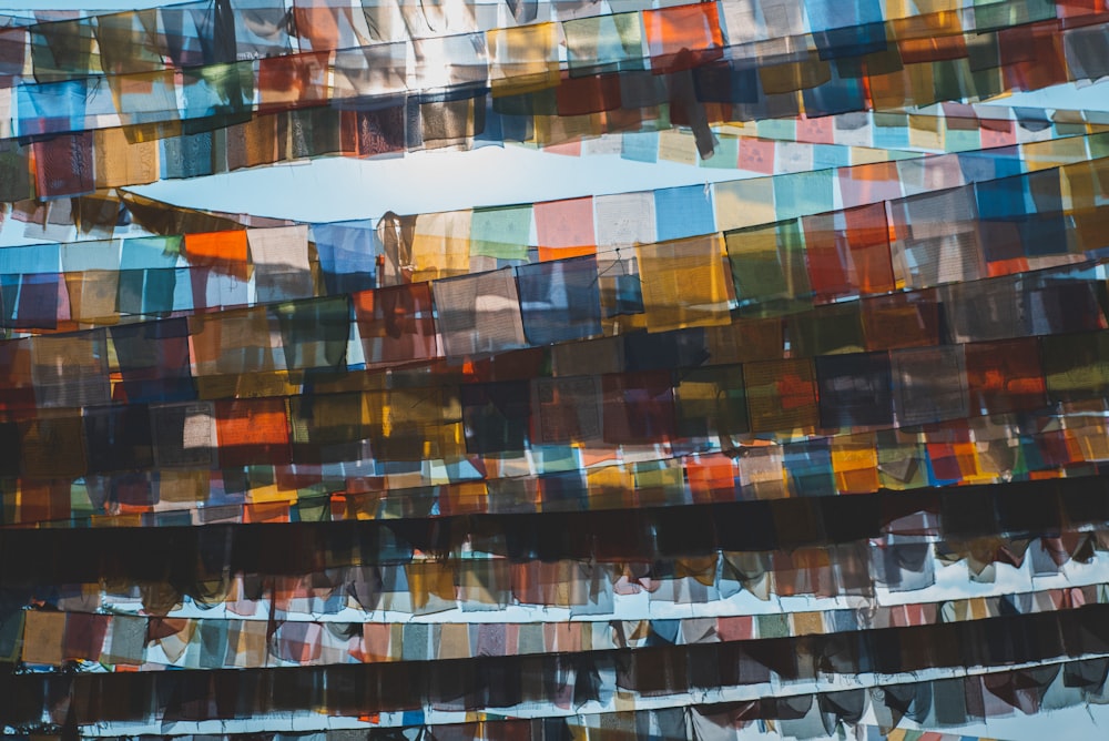 a bunch of colorful flags hanging from the side of a building