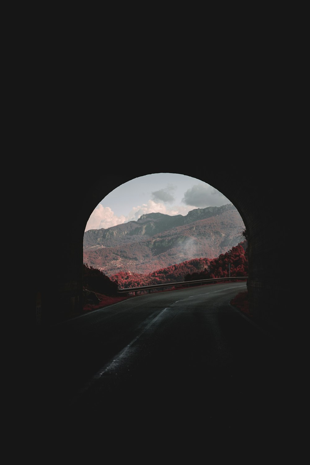 a dark tunnel with mountains in the background
