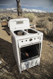 an old stove sitting in the middle of a dirt field