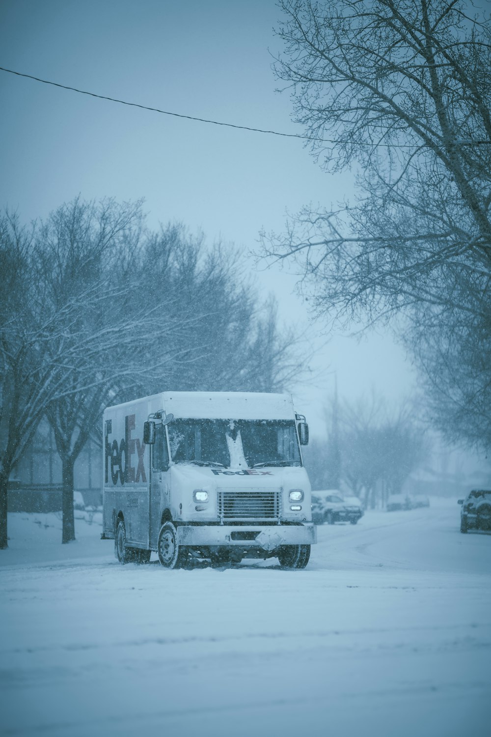 um caminhão branco dirigindo por uma rua coberta de neve