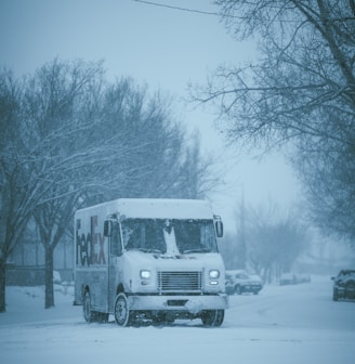 a white truck driving down a snow covered street