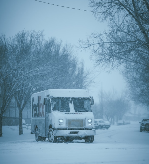 a white truck driving down a snow covered street