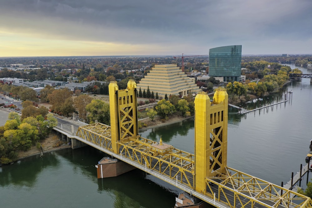 a large yellow bridge over a river next to a tall building