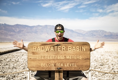 a man sitting on top of a wooden sign
