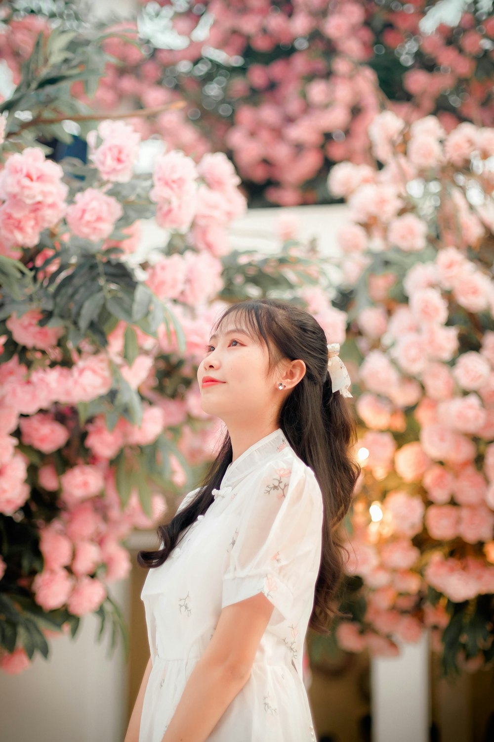 uma mulher em pé na frente das flores cor-de-rosa