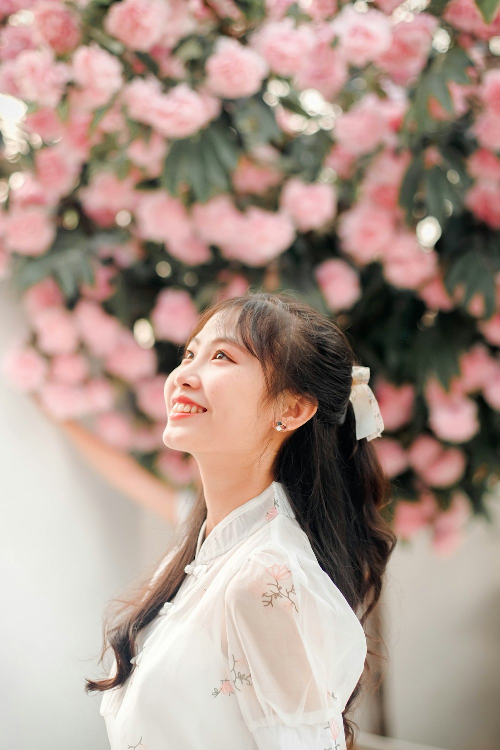 a woman standing in front of a bunch of pink flowers