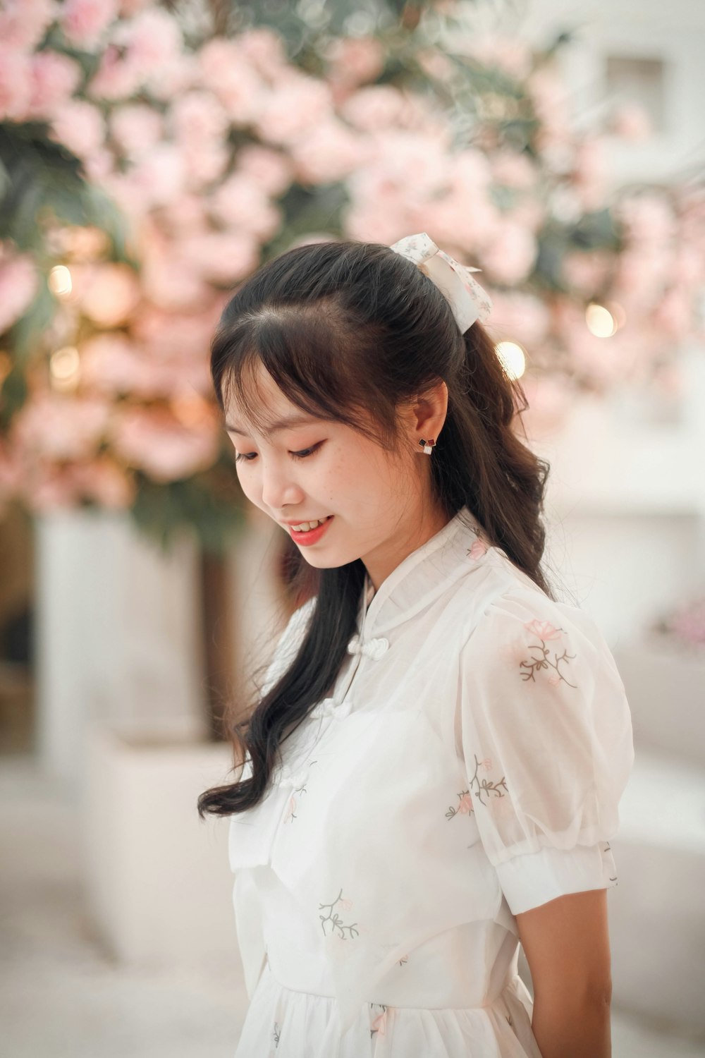 a woman in a white dress looking down at her cell phone