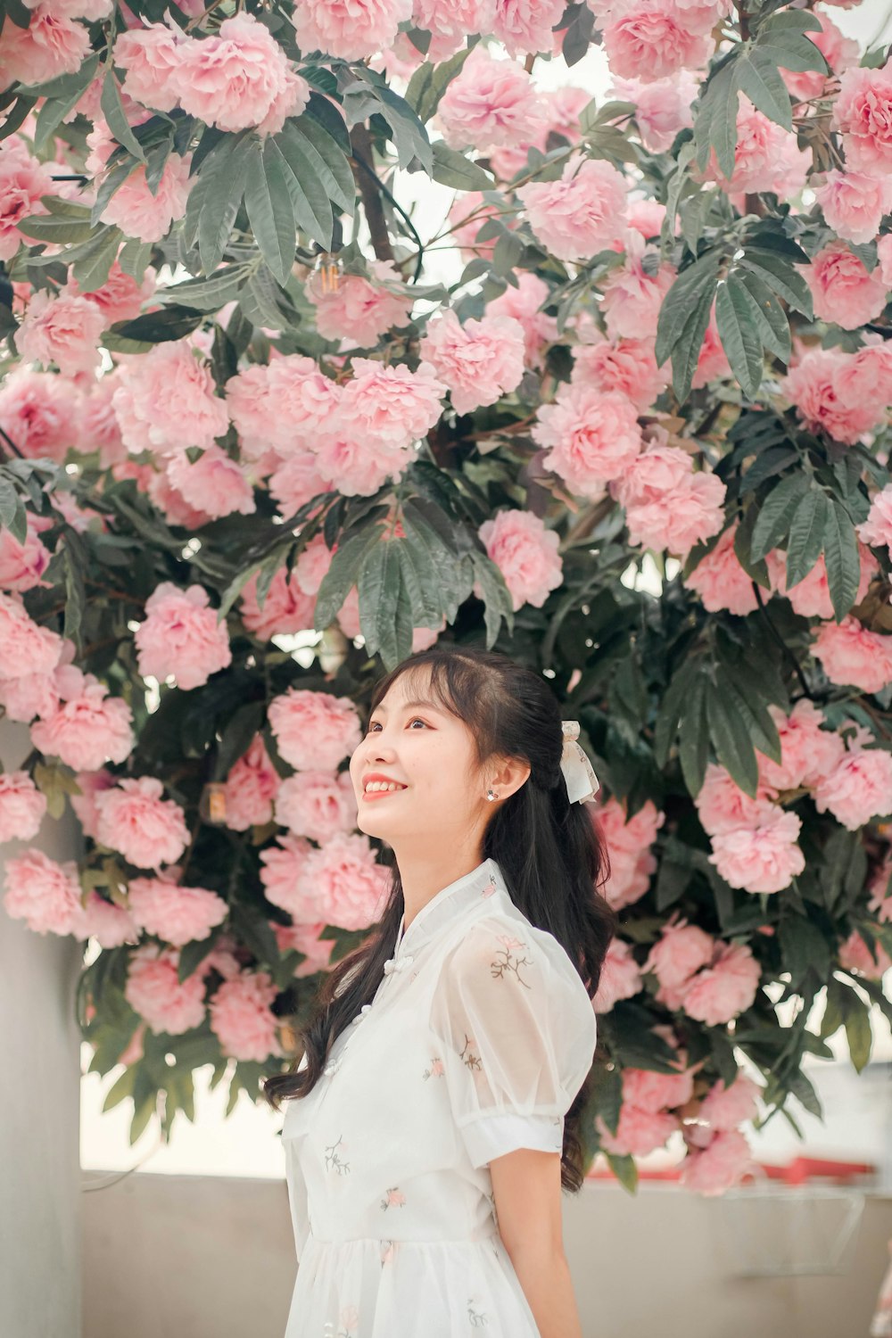 a woman standing in front of pink flowers