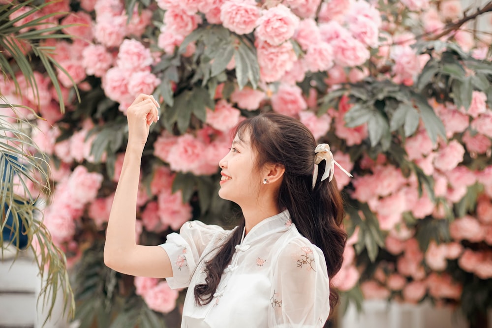 a woman standing in front of a wall of flowers