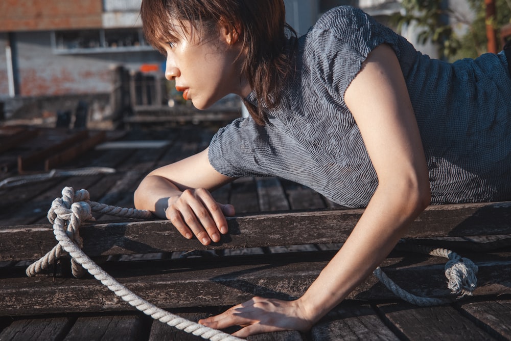 a woman laying on top of a wooden dock next to a rope