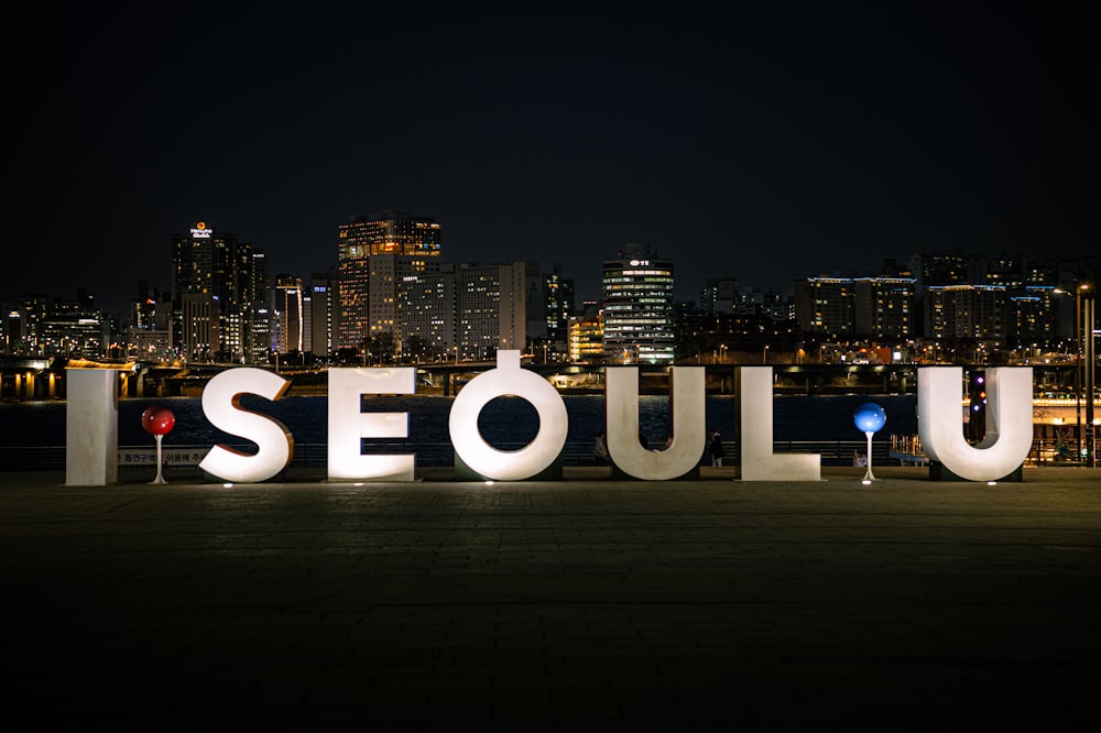 a sign that says seoul in front of a city skyline