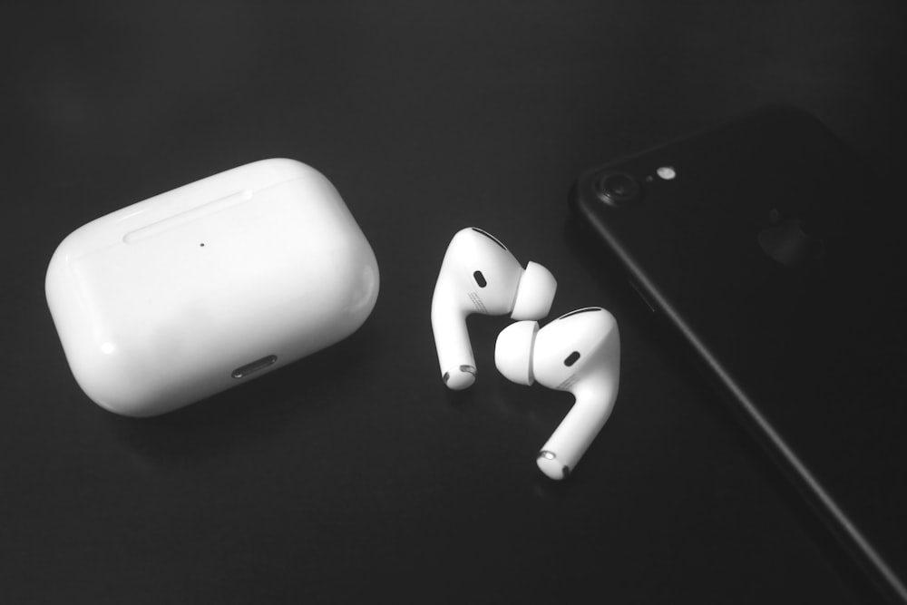 a pair of ear buds sitting next to an iphone