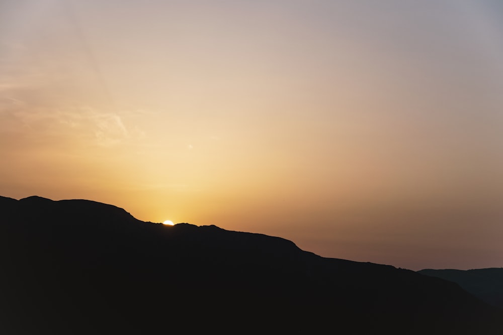 the sun is setting over a mountain range