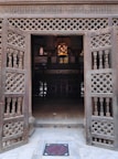 Intricately carved wooden door opening to a sunlit room with traditional decor.