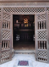 Intricately carved wooden door opening to a sunlit room with traditional decor.