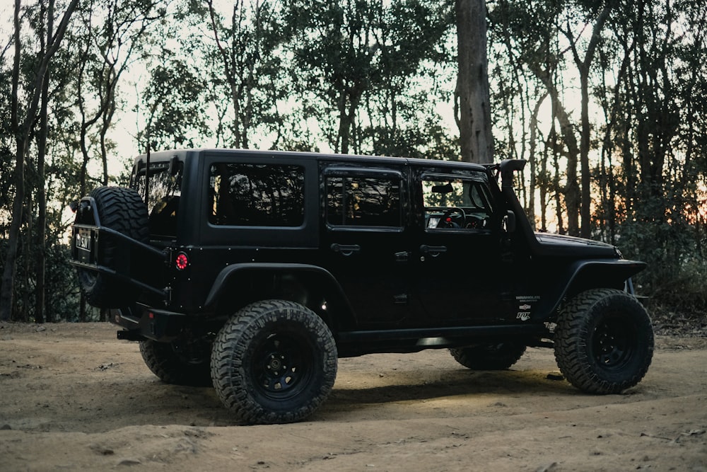 a black jeep is parked on a dirt road