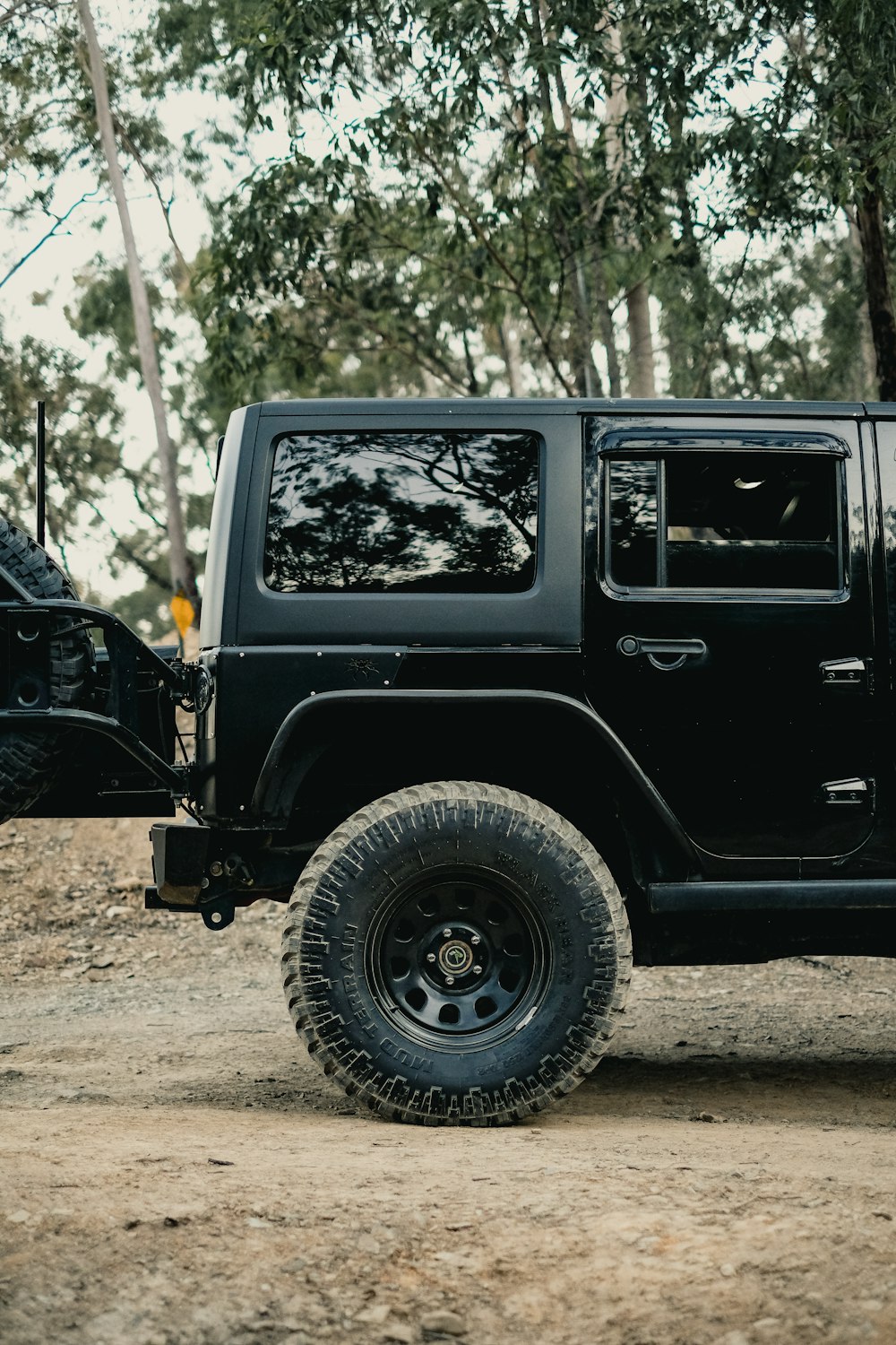 a black jeep is parked on a dirt road