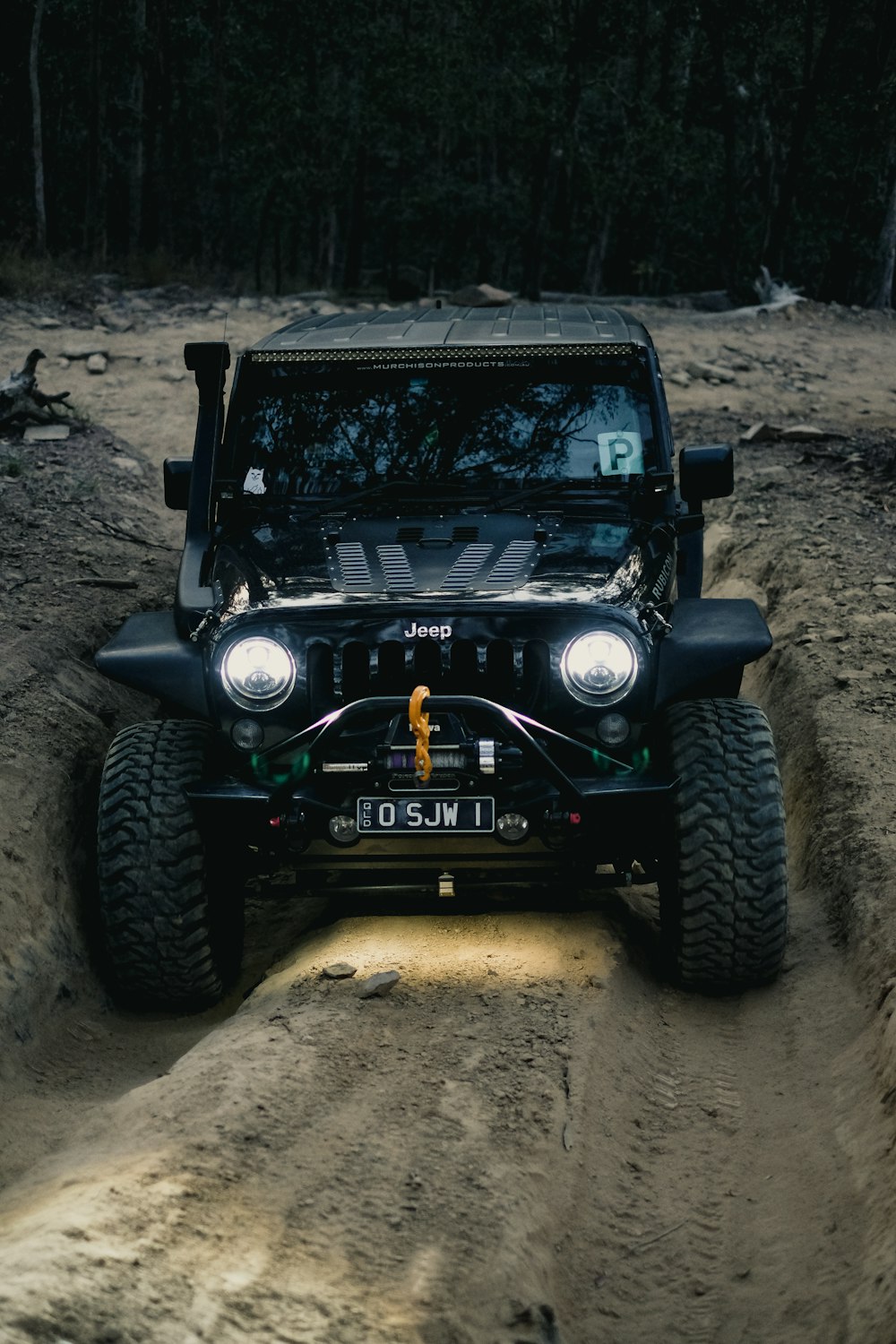 a jeep driving on a dirt road in the woods