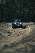 a jeep driving down a dirt road in the woods