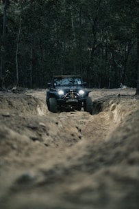 a jeep driving down a dirt road in the woods