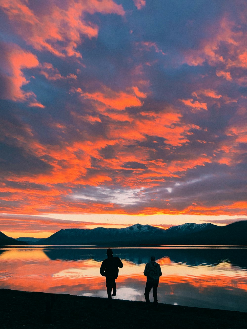 a couple of people standing next to a body of water