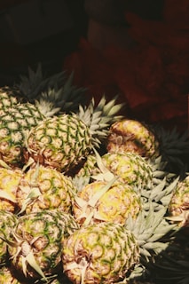 Golden dried pineapple rings stacked neatly with fresh green leaves in the background.