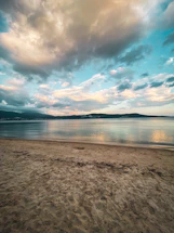 A serene beach scene under a cloudy sky with soft blue tones reflecting the calm atmosphere.